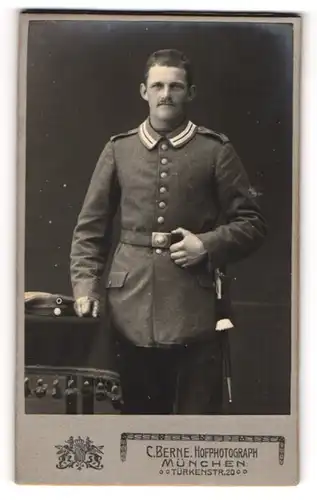 Fotografie C. Berne, München, Portrait Soldat in Uniform an Tisch gelehnt
