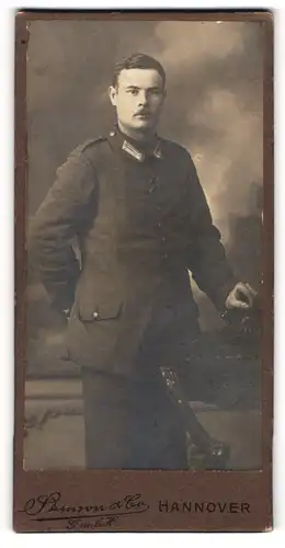 Fotografie Samson & Co., Hannover, Soldat mit Oberlippenbart steht hinter beschnitztem Stuhl