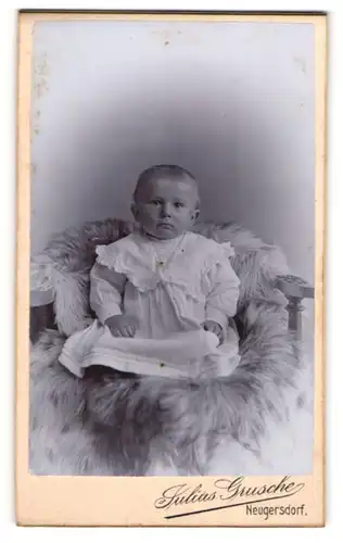 Fotografie Julius Grusche, Neugersdorf, kleines Kind in weissem Kleid auf Fell