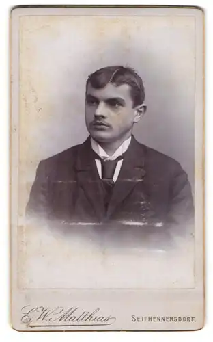 Fotografie E. W. Matthias, Seifhennersdorf, Mann mit Scheitelfrisur in Anzug und Krawatte