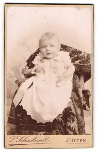Fotografie L. Schuchardt, Lützen, zuckersüsses blondes Kleinkind im weissen gerüschten Kleid
