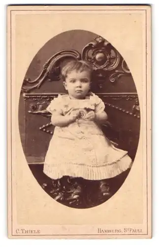 Fotografie C. Thiele, Hamburg, Junges Kind in Kleid sitzend