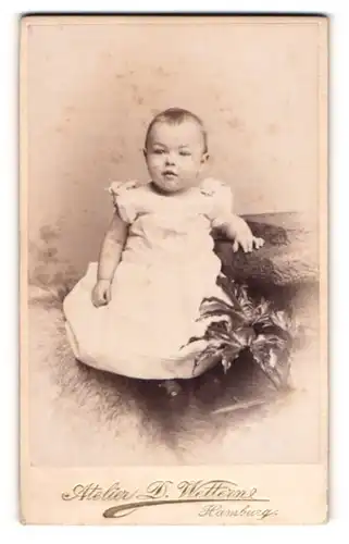Fotografie D. Wettern, Hamburg, Junges Kind in Kleid sitzend