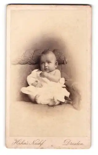 Fotografie G. Chr. Hahn Nachf., Dresden, Portrait sitzendes Baby im weissen Kleid mit nackigen Füssen