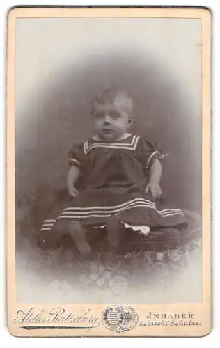 Fotografie Lebrecht Schulze, Ratzeburg, kleines Kind in gesteriften Kleid auf Hocker