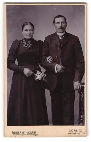 Fotografie Adolf Winkler, Görlitz, Ehepaar in schwarzen Gewändern mit Blumenstrauss