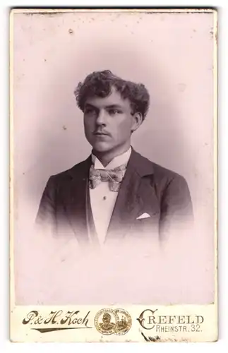 Fotografie P. & H. Koch, Crefeld, Portrait junger Herr im Anzug mit Fliege