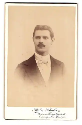 Fotografie E. W. Schulze, Hannover, Portrait junger Herr im Anzug mit Fliege und Schnurrbart