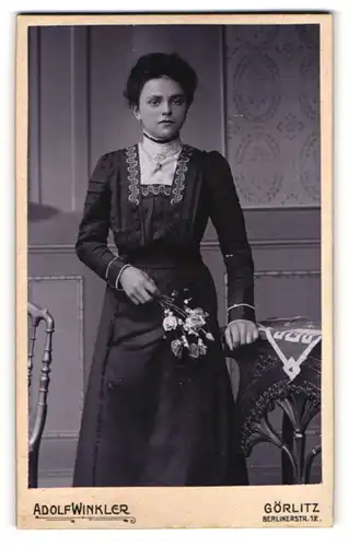 Fotografie Adolf Winkler, Görlitz, Portrait bürgerliche Dame mit Blumen an Tisch gelehnt