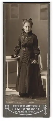 Fotografie Atelier Victoria, Ulm, junges Mädchen im dunklen Kommunionskleid mit Bibel