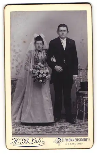 Fotografie H. B. Luh, Seifhennersdorf i. S., Brautpaar mit Brautstrauss im Hochzeitskleid und Anzug