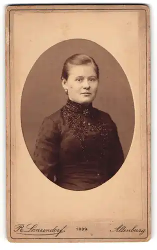 Fotografie R. Lanzendorf, Altenburg, Junge Dame in schwarzem Kleid mit Blumenmuster und dunkler Brosche