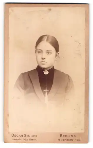 Fotografie Oscar Storch, Berlin, Friedrichstr. 125, Junge Dame in schwarzem Kleid mit weisser Brosche und Silberkette