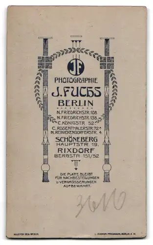 Fotografie J. Fuchs, Berlin, Jüngling in schwarzem Anzug mit Hut und Buch strammstehend