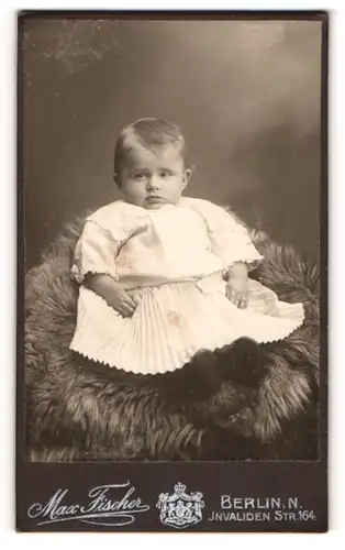 Fotografie Max Fischer, Berlin, Invaliden Str. 164, Niedliches Baby in weissem Kleid mit runden Backen und kleinen Augen