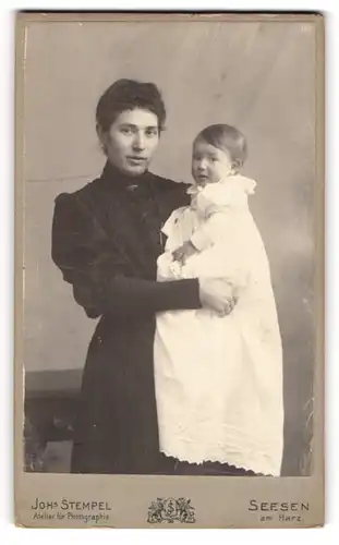 Fotografie Joh. Stempel, Seesen a. H., Mutter im dunklen Kleid mt Kind auf dem Arm, Mutterglück