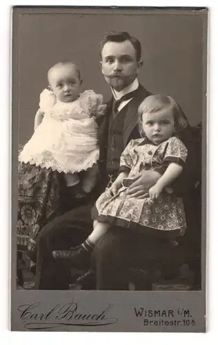 Fotografie Carl Bacuh, Wismar i. M., junger Vater mit seinen beiden Töchtern im Arm, stolzer Vater