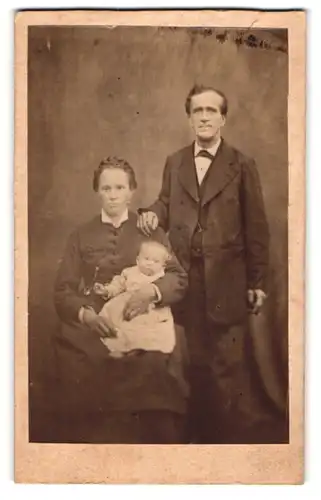 Fotografie Fotograf und Ort unbekannt, Mutter und Vater posieren mit Ihrer Kind auf dem Schoss, Mutterglück