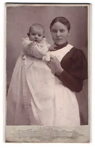 Fotografie F. Zinck, Hildburghausen, junge Mutter mit Schürze hält ihr Kind im Arm, Mutterglück