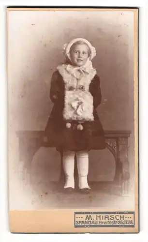 Fotografie M. Hirsch, Spandau, junges Mädchen im Winterkleid mit Muff und Wintermütze