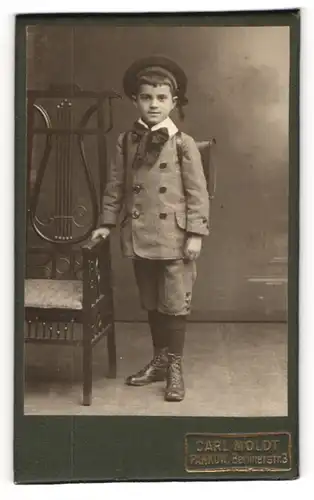 Fotografie Carl Moldt, Pankow, junger Knabe im Anzug mit Schulranzen zum Schulanfang