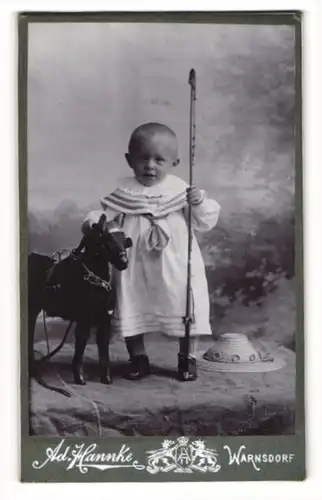 Fotografie Ad. Hannke, Warnsdorf, Kleinkind mit Spielzeugpferd und langer Peitsche