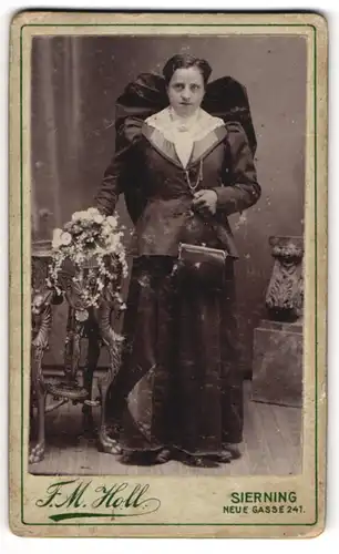 Fotografie F. M. Holl, Sierning, junge Frau im dunklen Kleid mit Trachtenschleife und Handtasche