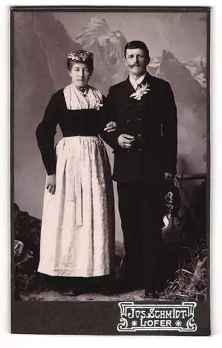 Fotografie Jos. Schmidt, Lofer, österreichisches Paar im Trachtenkleid und Anzug vor einer Studiokulisse
