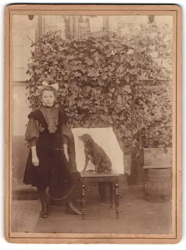 Fotografie unbekannter Fotograf und Ort, junges Mädchen im Samtkleid nebst ihrem Hund auf dem Stuhl, 1908