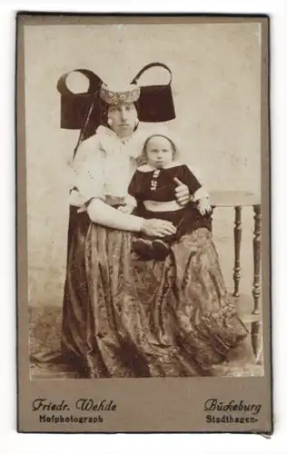 Fotografie Friedr. Wehde, Bückeburg, Mutter in Bückeburger Tracht mit ihrem Kind auf dem Schoss