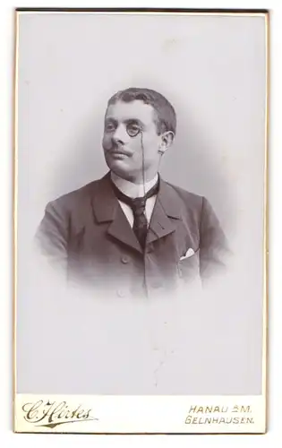 Fotografie C. Hirtes, Hanau a. M., Portrait junger Herr im Anzug mit Krawatte und Monokel