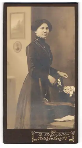Fotografie R. Schönfelder, Reichenbach i / V., Portrait junge Dame im schwarzen Kleid mit Blumen an Stuhl gelehnt