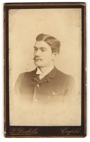 Fotografie G. Diebels, Crefeld, Portrait junger Herr in modischer Kleidung mit Zwirbelbart