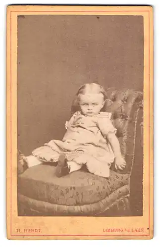 Fotografie H. Hardt, Limburg a / d. Lahn, Portrait kleines Mädchenim hübschen Kleid auf Sessel sitzend