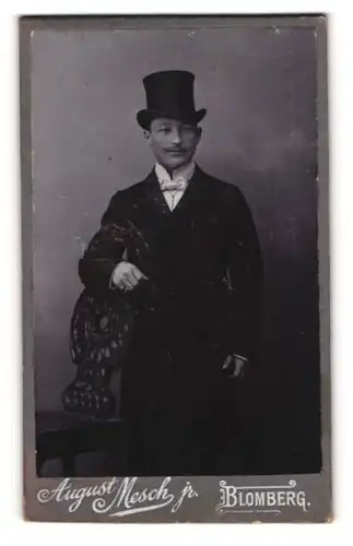 Fotografie August Mesch jr., Blomberg, Portrait elegant gekleideter Herr mit Zylinderhut an Stuhl gelehnt