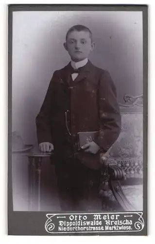 Fotografie Otto Meier, Dippoldiswalde, Portrait junger Mann im Anzug mit Fliege und Buch in der Hand