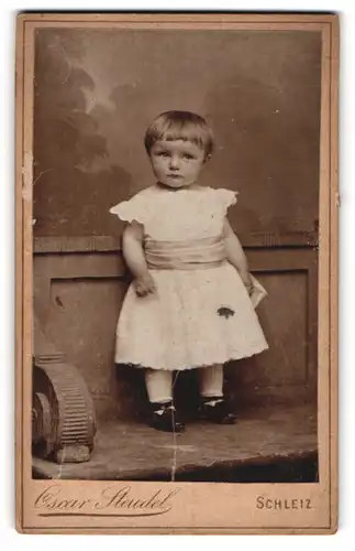 Fotografie Oscar Steudel, Schleiz, Portrait kleines Mädchen im weissen Kleid auf Bank stehend