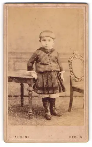 Fotografie E. Faehling, Berlin, Portrait kleines Mädchen im modischen Kleid an Tisch gelehnt