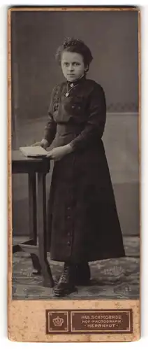 Fotografie Hch. Schmorrde, Herrnhut, Portrait junge Dame im schwarzen Kleid mit Buch an Tisch gelehnt