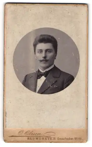 Fotografie O. Olesen, Neumünster, Portrait junger Herr im Anzug mit Fliege und Schnurrbart