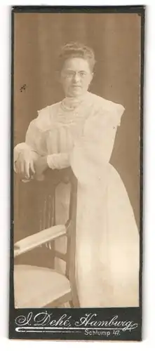Fotografie J. Dehé, Hamburg, Portrait weiss gekleidete Dame mit Zwicker an Stuhl gelehnt