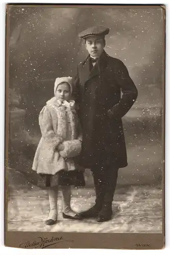 Fotografie Atelier Medina, Wien, junger Mann mit seiner kleinen Schwester im Winterkleid mit Muff, Schnee Montage, 1910