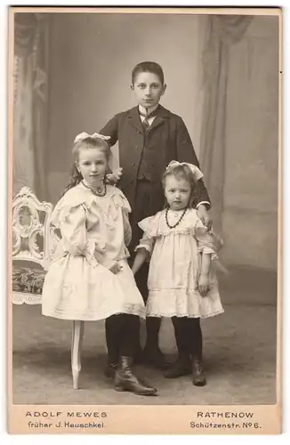 Fotografie Adolf Mewes, Rathenow, junger Knabe mit seinen beiden Schwestern in weissen Kleidern mit Haarschleife