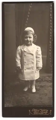 Fotografie Albin Uhlig, Aue i. Erzg., niedliches kleines Mädchen im Wintermantel mit Hut und Locken