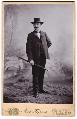 Fotografie Max Steffens, Berlin, junger Mann im Anzug mit Schirm und Hut, Mustasch