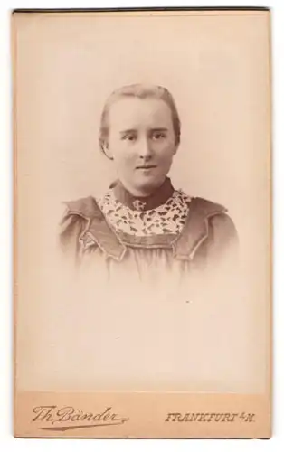 Fotografie Th. Bänder, Frankfurt a. M., Schillerplatz 4, Junge Dame in gemustertem Kleid mit hellen Haaren und Brosche