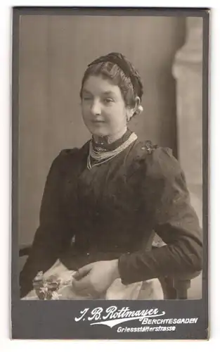 Fotografie J. B. Rottmayer, Berchtesgaden, Griessstätterstr., Junge Dame in schwarzem tailliertem Kleid mit Silberketten