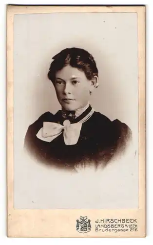 Fotografie J. Hirschbeck, Landsberg a. Lech, Brudergasse 216, Junge schöne Frau in schwarzem Kleid mit weisser Fliege
