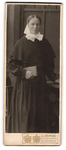 Fotografie C. Remde, Eisenach, Junge Frau in Trachtenkleid mit zurückgesteckter Frisur und Buch in der Hand