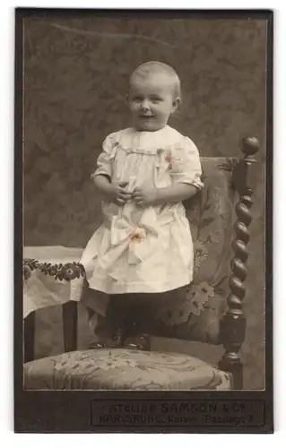 Fotografie Samson & Co., Karlsruhe, Portrait kleines Mädchen im weissen Kleid auf Stuhl stehend